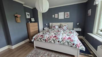A bedroom with a bed, dresser, nightstands, and a window.