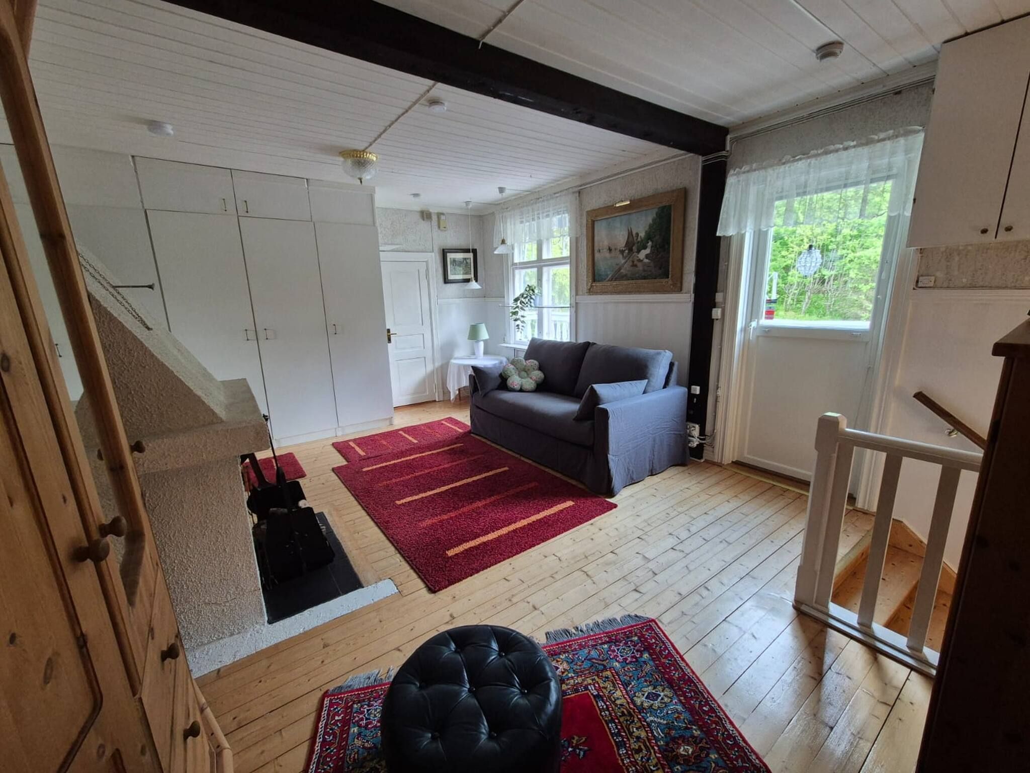 A spacious living area with a sofa, a red rug, and a black ottoman.