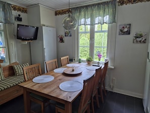 Un comedor con una mesa de madera, sillas y un televisor montado en la pared.