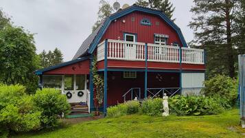 A red barn with a blue roof, a balcony, and a small porch.