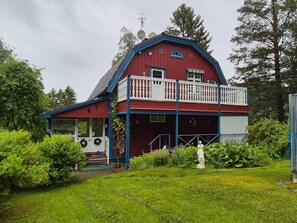 A red barn with a blue roof, a balcony, and a small porch.