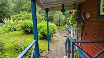 A covered outdoor area with a wooden deck, a statue, and a garden with various plants.