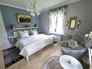 A bedroom with a bed, bedside tables, a chair, a small table, a mirror, and a window with curtains. - Holiday House With Lots of Charm (Lunde)