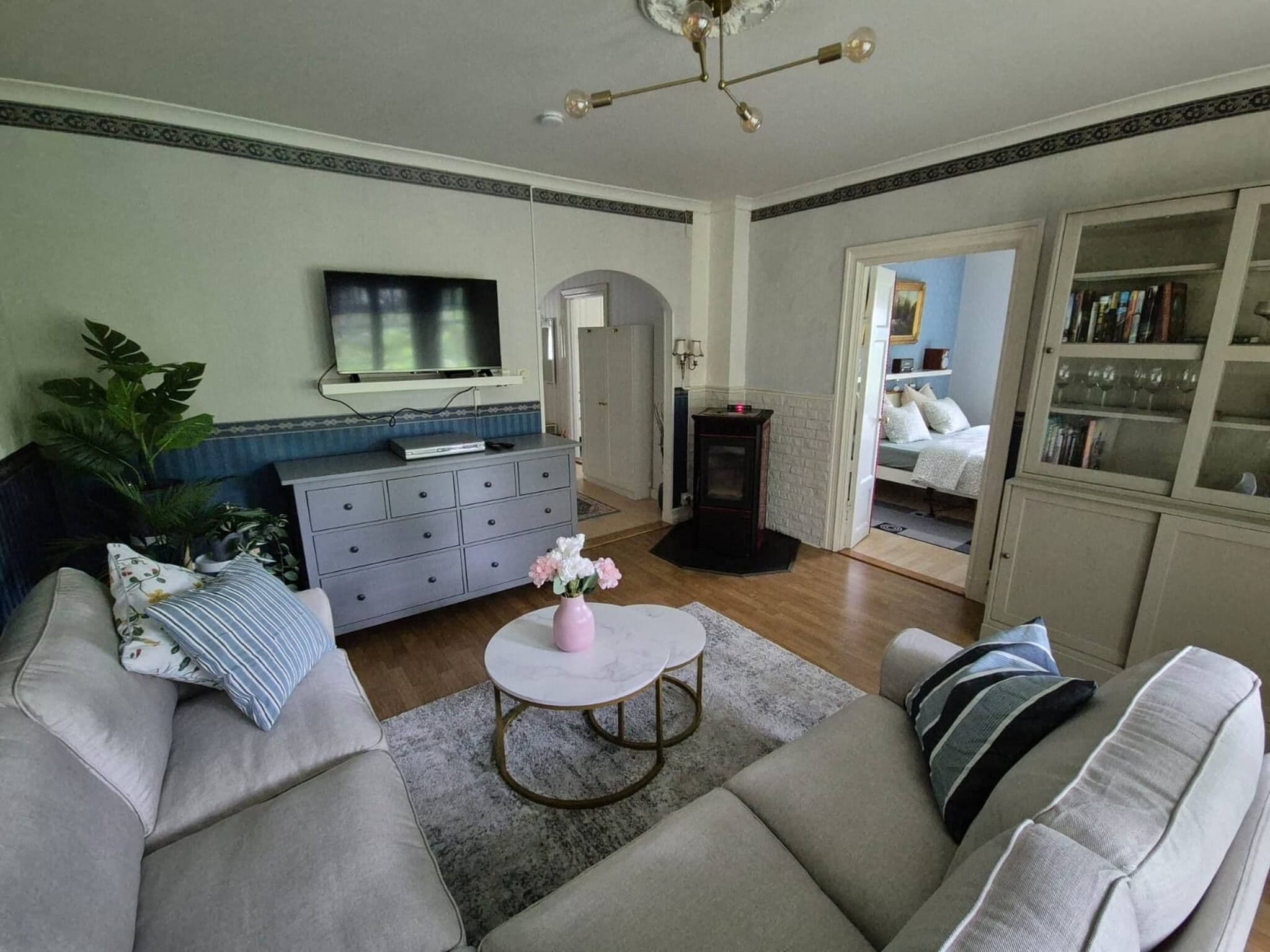Ein Wohnzimmer mit einer Couch, einem Couchtisch, einem Fernseher und einem Bücherregal.