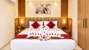 Een hotelkamer met een groot bed, twee nachtkastjes, een wandairconditioner, een plafondventilator en een houten garderobe.