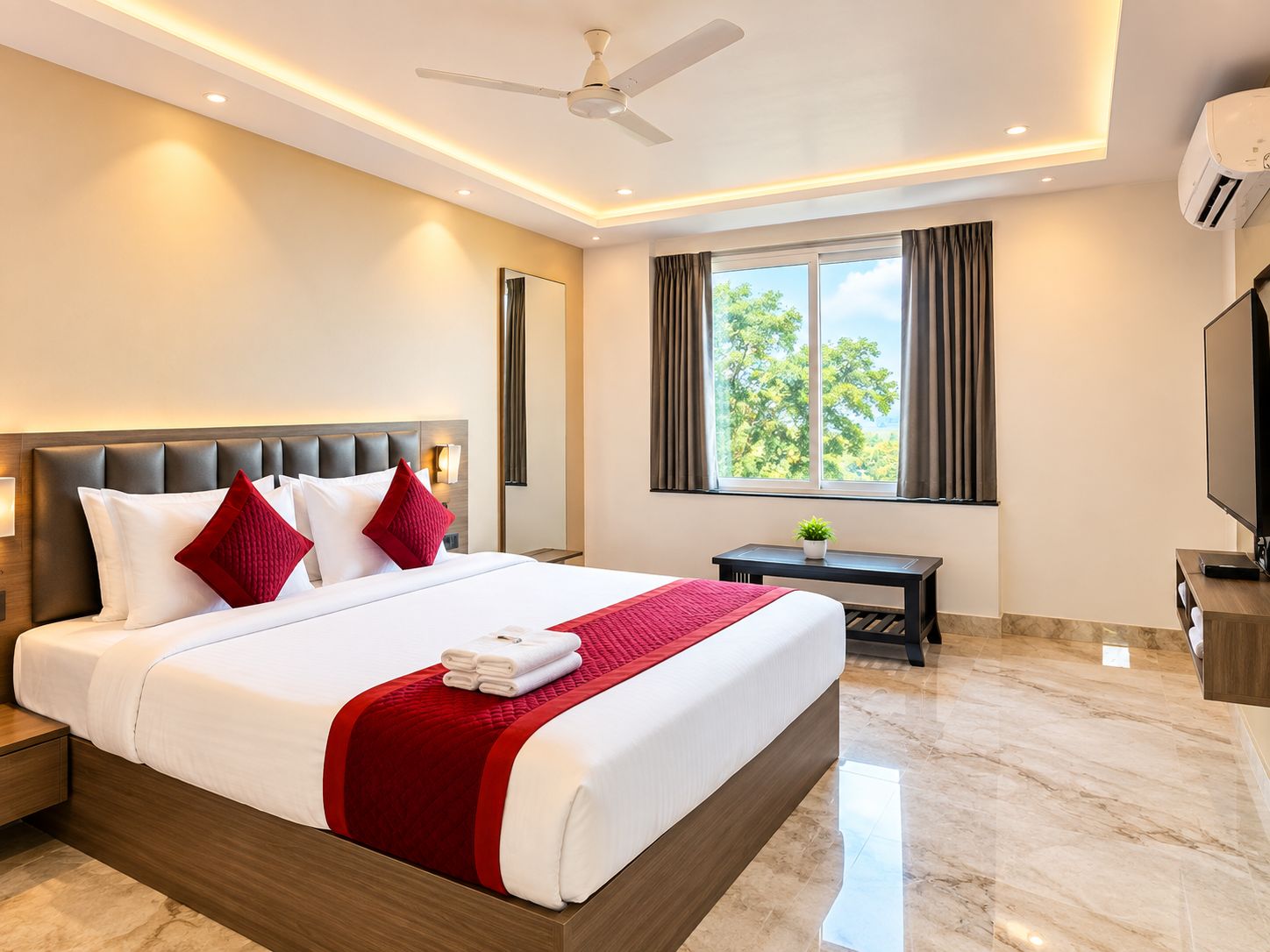 Habitación de hotel con una cama grande, ventilador de techo, equipo de aire acondicionado, televisor y ventana con cortinas.