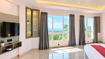 Een moderne hotelkamer met een groot bed, een flatscreen televisie, een inbouwkast en uitzicht op de oceaan.