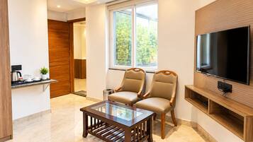 Una sala de estar moderna con una mesa de centro de vidrio, dos sillones de cuero, un televisor de pantalla plana y un mueble de televisión de madera.