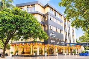 Un hotel de varios pisos con fachada moderna, un restaurante visible llamado 'Chuck N Fish Family Restaurant' y un área exterior bien cuidada con plantas en macetas.