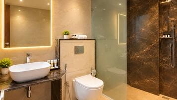 Un baño moderno con un espejo grande, un lavamanos independiente, inodoro y zona de ducha con mampara de cristal.