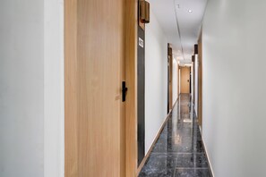 A hallway with wooden doors and a tiled floor. - Collection O Adajan Formerly Hotel Sky (Surat)