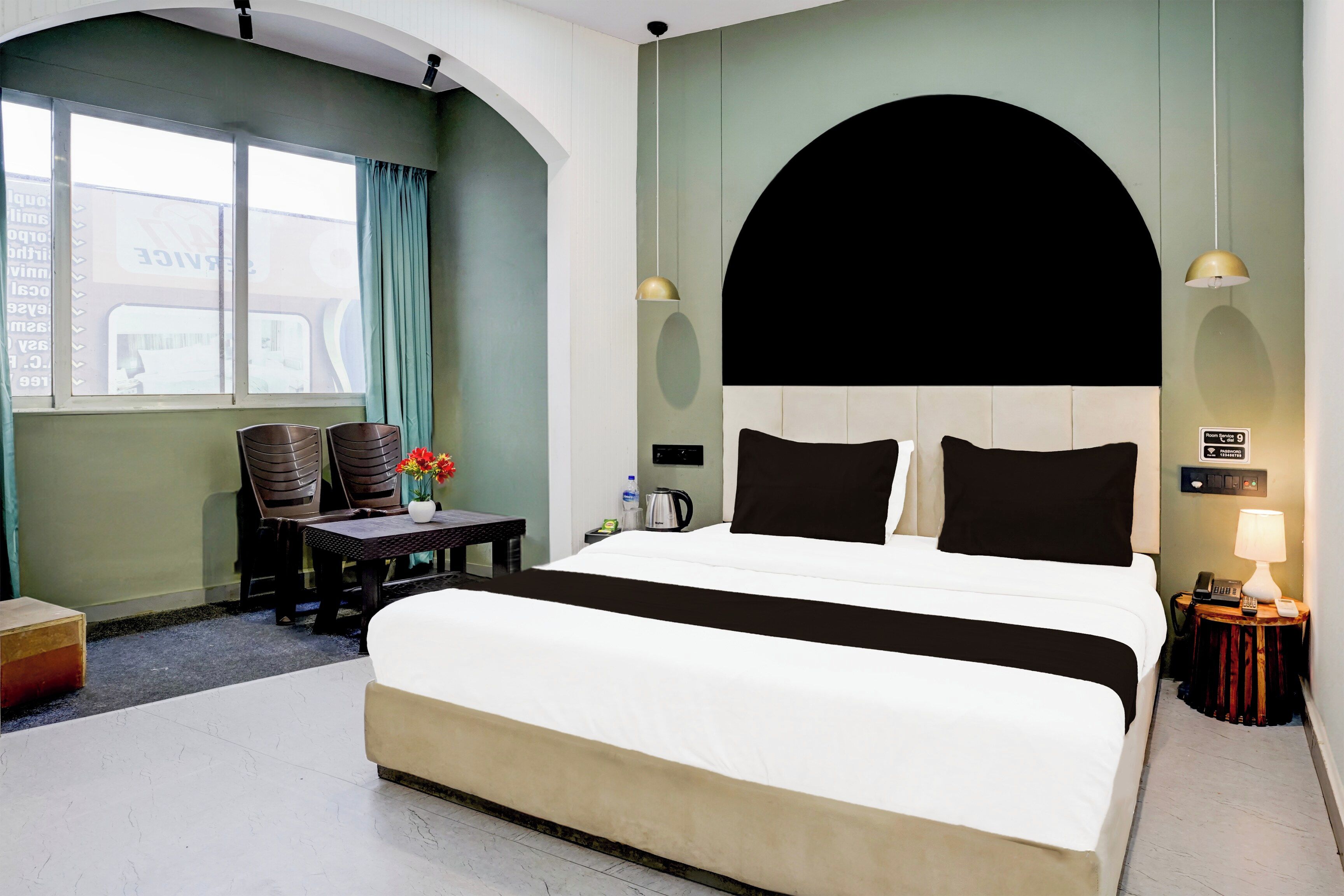 Habitación de hotel con cama, escritorio, sillas, ventana y vista al exterior.