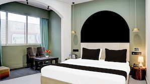 Ein Hotelzimmer mit Bett, Schreibtisch, Stühlen, einem Fenster und Blick nach draußen.