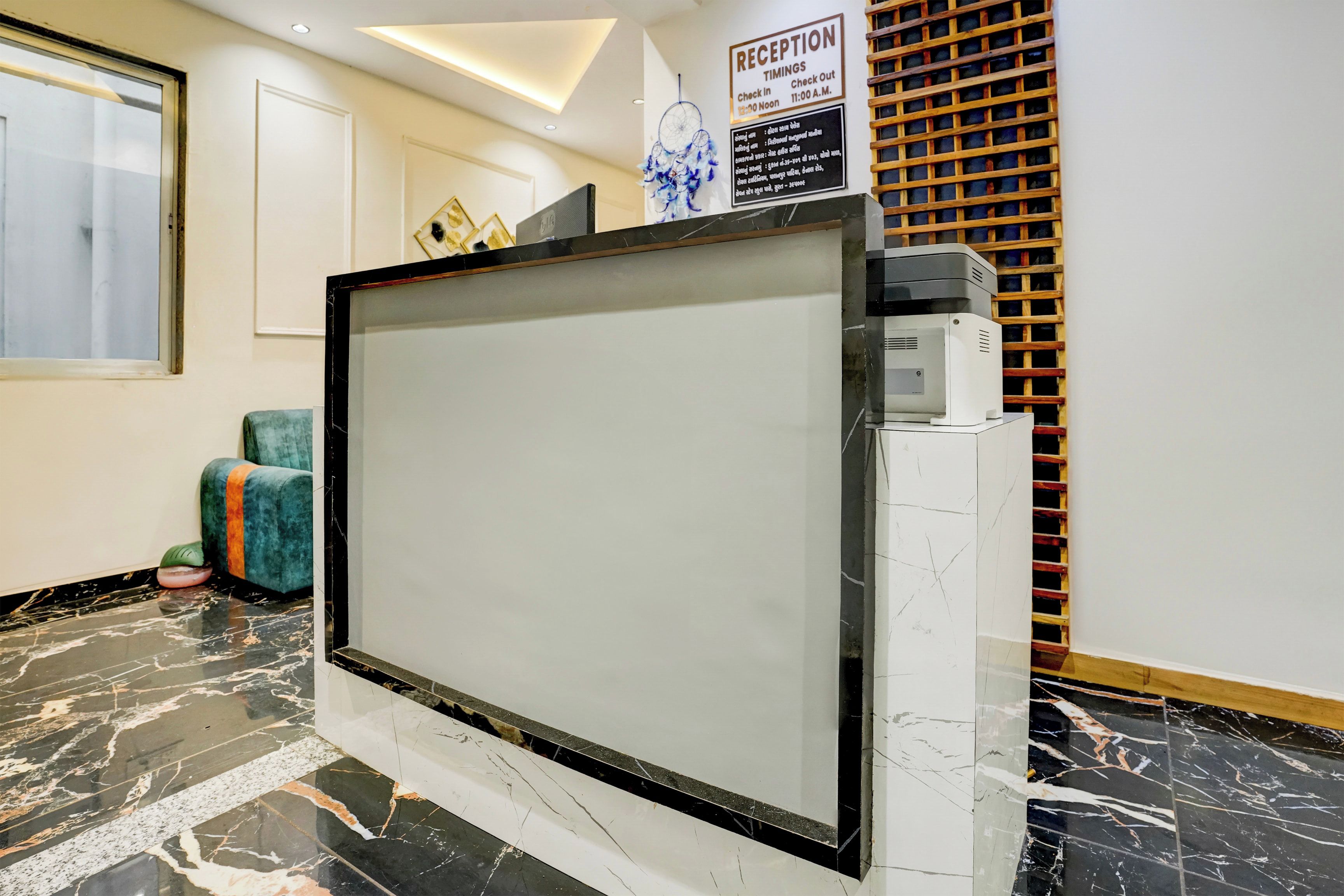 Un mostrador de recepción con una pantalla digital, un letrero de recepción e impresora mural.