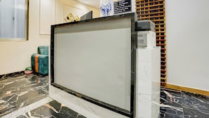 Ein Empfangsschalter mit einem digitalen Bildschirm, einem Empfangsschild und einem Wanddrucker.
