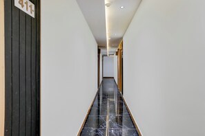 A hallway with a black marble floor, white walls, and a door with a number sign.