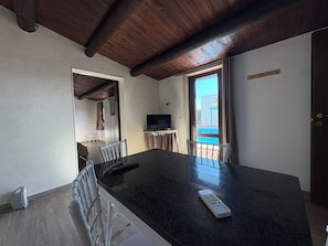 Habitació amb un taulell gran de color fosc, televisió i vista a una piscina a través d'una porta de vidre.