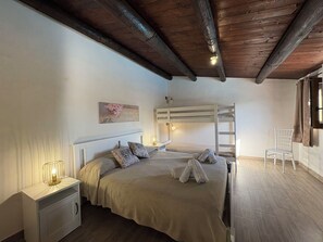 A bedroom with a bunk bed, a bedside table with a lamp, a chair, and a painting on the wall. - Il Cigno Reale White (Chiaramonte Gulfi)