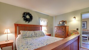 A bedroom with a bed, two nightstands, a dresser, a mirror, and a door leading to another room. - Private Beach Access! Lake Champlain Cabin (Plattsburgh)