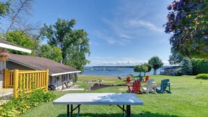 A lakeside property with a deck, outdoor seating, and a view of boats on the water. - Private Beach Access! Lake Champlain Cabin (Plattsburgh)