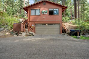 Eine zweistöckige Lodge mit Garage, Holzfassade und einem Schild mit der Aufschrift 'Tall Tree Lodge'.