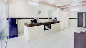 A hotel reception area with a reception desk, a computer, and a wall-mounted fan.