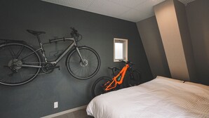 A bedroom with a bed, two bicycles, a window, and a ceiling with a grid pattern. - Ted's guesthouse (Uchiko)