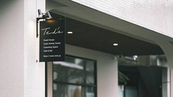 A building with a sign indicating it is a guest house, cycle activity center, coworking space, café & bar, and includes a URL.