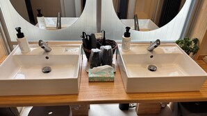 A bathroom with two sinks, a mirror, and toiletries. - Ted's guesthouse (Uchiko)