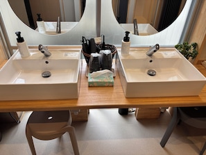 A bathroom with two sinks, a mirror, and toiletries. - Ted's guesthouse (Uchiko)