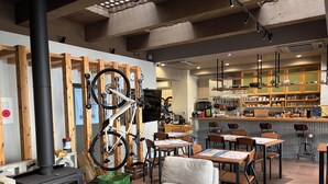 A cozy interior with a wood-burning stove, seating area, and a bar with kitchen in the background. - Ted's guesthouse (Uchiko)