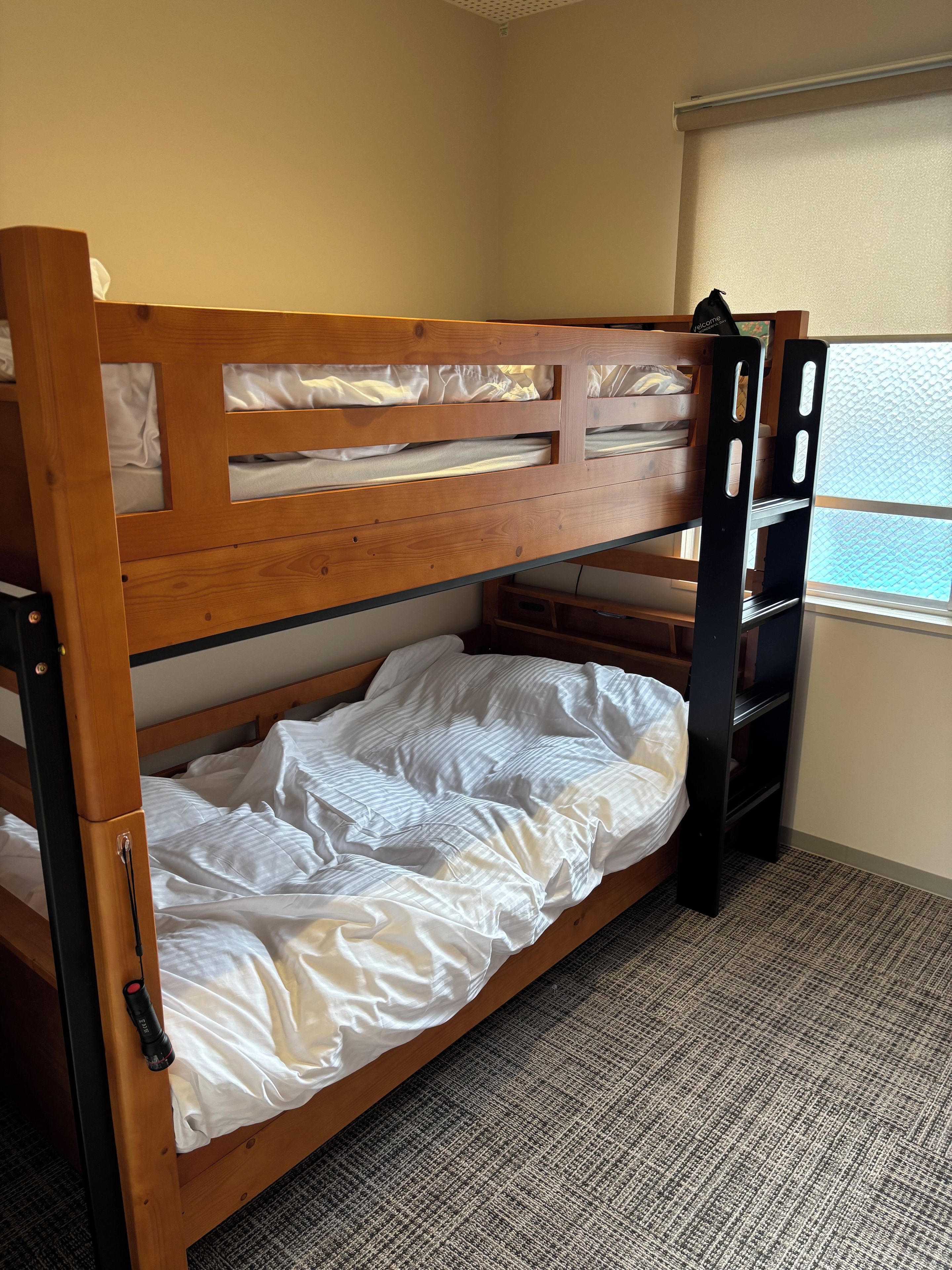 A bunk bed with a wooden frame, a mattress, and a pull-out desk.