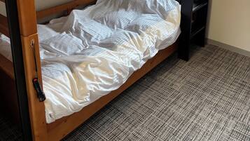 A bunk bed with a wooden frame, a mattress, and a pull-out desk.