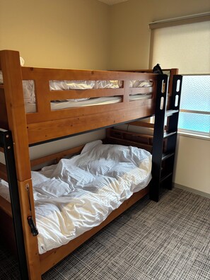 Una cama litera con estructura de madera, un colchón y un escritorio plegable.