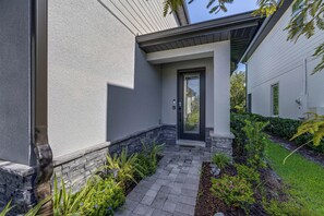 Ein modernes Haus mit Steinuntergrund, einem gepflasterten Weg und einer schwarzen Tür.
