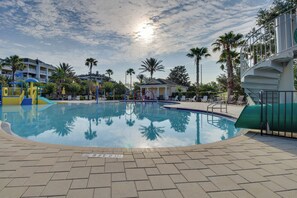 A swimming pool with a 3ft 2in depth marker, surrounded by palm trees and a playground with slides. - 10 Mi to Disney & Old Town! Stylish Family Home (Kissimmee)