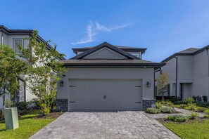 Une propriété résidentielle dotée d’un garage, d’une allée pavée et d’un jardin aménagé.