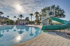 A swimming pool with a green slide, surrounded by palm trees and lounge chairs. - 10 Mi to Disney & Old Town! Stylish Family Home (Kissimmee)