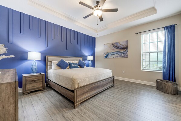A bedroom with a bed, nightstands, a ceiling fan, a window with curtains, and a wall-mounted painting. - 10 Mi to Disney & Old Town! Stylish Family Home (Kissimmee)