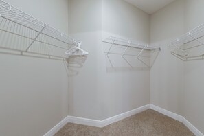 A corner of a room with a white wall, a beige carpet, and a white wire shelf unit. - 10 Mi to Disney & Old Town! Stylish Family Home (Kissimmee)