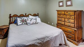 Ein Schlafzimmer mit einem hölzernen Bett, einem Schminktisch und zwei gerahmten Zertifikaten an der Wand.