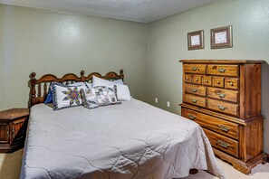 Ein Schlafzimmer mit einem hölzernen Bett, einem Schminktisch und zwei gerahmten Zertifikaten an der Wand.