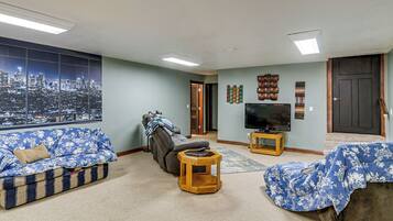 A living room with a cityscape view, a reclining chair, a flat-screen TV, and a wooden coffee table.
