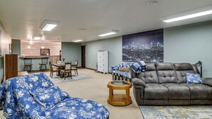 Ein Wohnzimmer mit einer Couch, einem Esstisch mit Stühlen und einer Wand mit Stadtansicht.