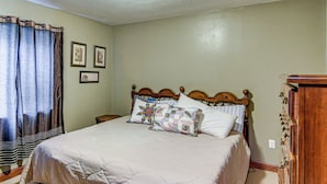 Quarto com uma cama grande, cabeceira de madeira, mesa de cabeceira e cômoda.