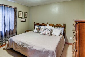 Un dormitorio con una cama grande, cabecera de madera, mesita de noche y cómoda.
