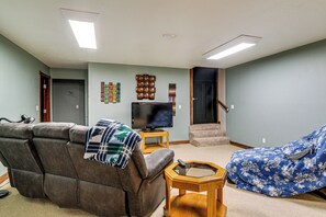 A living room with a brown leather sofa, a blue patterned chair, a television, and a small wooden side table.