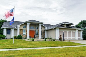 Ein zweistöckiges Haus mit Steinaußenwand, einer großen Garage und einem gepflegten Rasen.