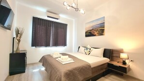 Une chambre moderne avec un lit, une table de chevet, une lampe, un climatiseur et un tableau au mur.