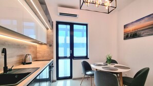 Une cuisine moderne équipée d’un four encastré, d’un évier et d’un coin repas avec une table ronde et des chaises.